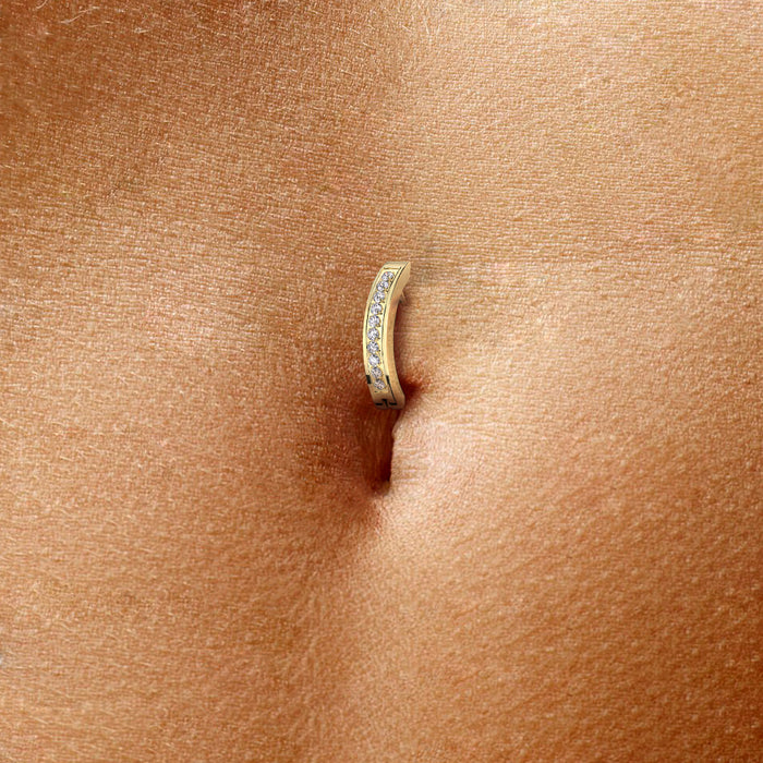 Close-up van gedragen navelpiercing met pvd goudkleurig titanium